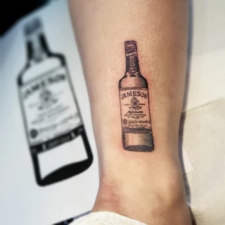 Tatouage Jameson bouteille microrealism -  - Tatouage Irlandais et Celtique - Black Hat Tattoo Nicesur les cotes - Tatouage Ornemental - Black Hat Tattoo Nice  - tatouage Nice - The Black Hat Tattoo